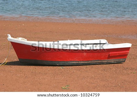 A wooden row boat on the beach at low tide.