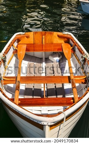 Wooden rowboat at dock with brightwork oars and trim. Coastal Maine, USA.