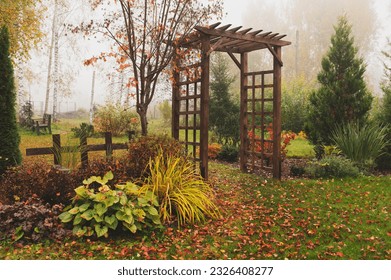 wooden rustic archway in autumn natural garden. Foggy october day