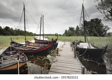 Wooden sailing boats moored to a pier. Birka, Björkö island, lake Mälaren, Sweden. Atmospheric landscape. Travel destinations, landmarks, sightseeing, history, historical reenactment, viking age