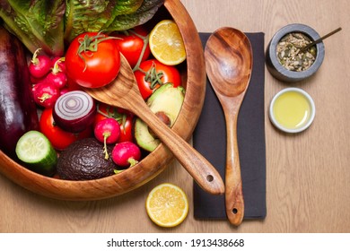 Wooden salad bowl and servers with all the row ingredients with black napkins and some oil with seed mixed - Powered by Shutterstock