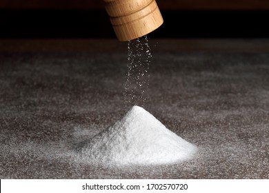 Wooden salt grinder and pile of salt. Salt falls from the grinder on a table full of salt.  - Shutterstock ID 1702570720