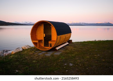 Wooden sauna on a beach during sunset or sunrise on a lake in Troms county in northern Norway. Sauna cabin.