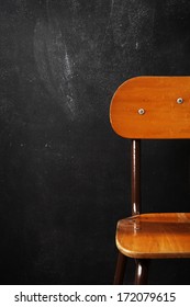 Wooden school chair against blackboard