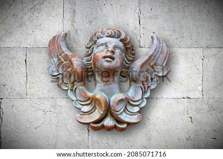 Wooden sculpture of an italian angel against a stone wall