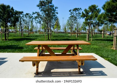 Wooden seat in a city park. Picnic in the park. Rest in the open area. 
Wooden picnic table and seats.