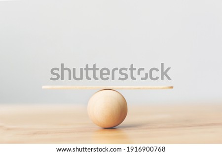 Wooden seesaw scale empty balancing on wooden sphere on wood table