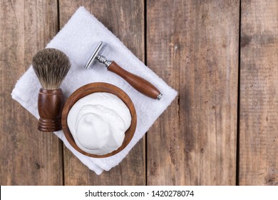 
				Wooden shaving razor with shaving brush and shaving foam on a rustic wooden table - vintage shaving accessories - top view
