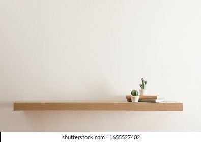 Wooden shelf with books and decorative cactuses on light wall - Shutterstock ID 1655527402