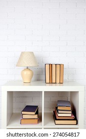 Wooden shelf with books and lamp on brick wall background - Shutterstock ID 274054817
