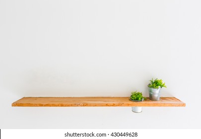 Wooden shelf on white wall with green plant. - Shutterstock ID 430449628