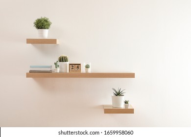 Estantes de madera con hermosas plantas y calendario en pared clara