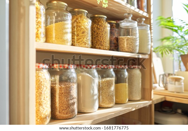 Wooden shelves in pantry for food storage, grain\
products in storage\
jars.