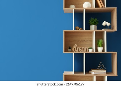 Wooden shelving unit with books and decor near blue wall - Shutterstock ID 2149706197