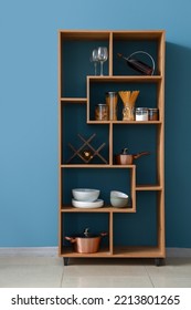 Wooden Shelving Unit With Food And Dinnerware Near Blue Wall