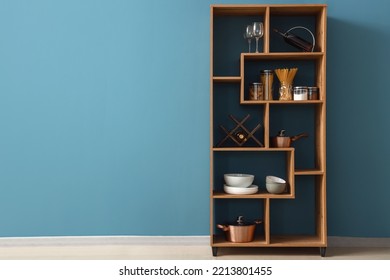 Wooden Shelving Unit With Food And Dinnerware Near Blue Wall