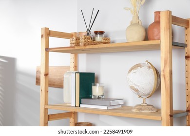 Wooden shelving unit with home decor near light wall - Shutterstock ID 2258491909
