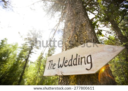 Wooden sign pointing towards a wedding ceremony