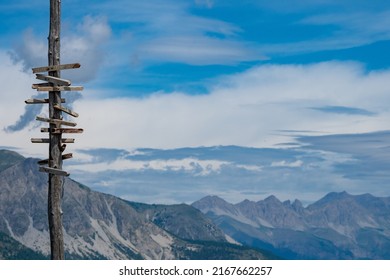 Wooden Sign Post At Summit Of Mountain In The Alps Showing The Direction Of Hiking Trails