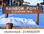 Wooden sign for Rainbow Point in Bryce Canyon National Park in snow during winter.
