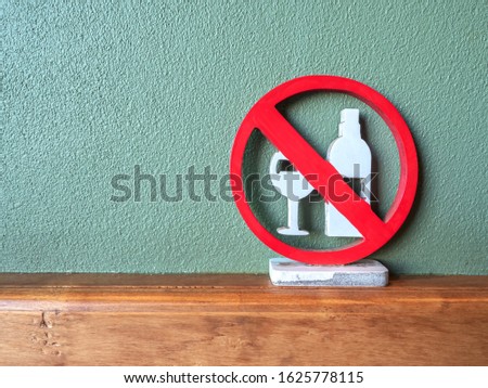 Wooden signage alcohol drink disallowed  area painted red and white color, put on wooden wall border with green rough stucco wall background.