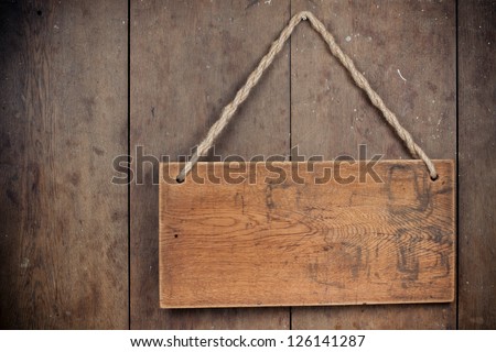Wooden signboard with rope hanging on grunge planks background