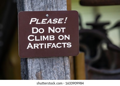 A wooden signboard with text - Please do not climb on artifacts hanged in the museum, Kootenays, British Columbia, Canada