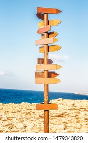 Wooden signpost on the background of the sea and blue sky on a sunny day. Vertical.