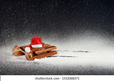 Wooden Sled On White Snow On A Black Background, With A Red Santa Hat, Side View