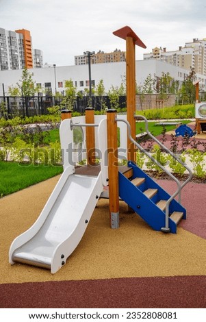 A wooden slide of white blue color with a canopy on the playground in kindergarten on a clear sunny day. Playgrounds, toys, sports.