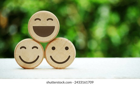 Wooden smile emoji with natural bokeh background. International Day of Happiness and mental health concept.
