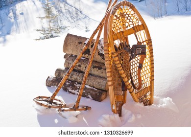 Wooden Snow Shoes And Snow Poles Leaning Against A Stack Of Cut Firewood In The Snow.