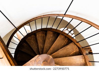 Wooden spiral staircase with white wall. Top view.