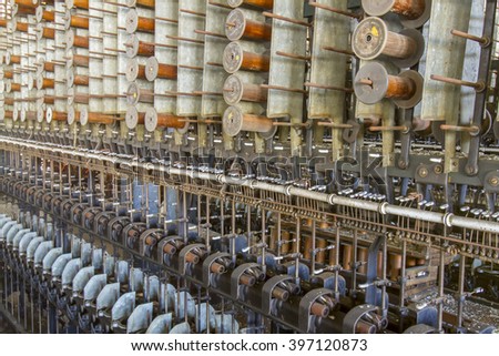 Wooden spools and bobbins on machinery in turn of the century silk throwing factory.