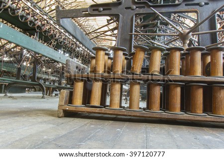 Wooden spools next to antique equipment in turn of the century silk throwing factory.