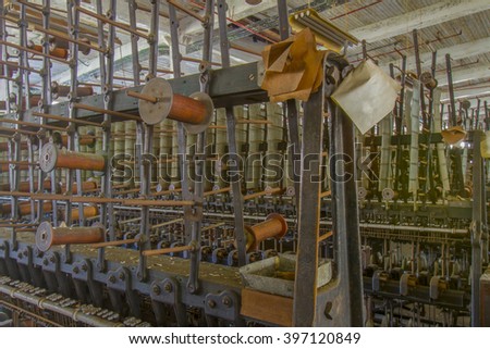 Wooden spools on thread throwing matching on floor of turn of the century silk throwing factory.