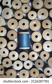 Wooden Spools Of Thread Are Laid Out Around A Blue Bobbin Of Thread. A Pattern Of Antique Sewing Accessories. Top View, Close-up, Macro..