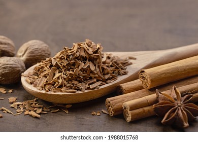 Wooden Spoon With Crushed Cinnamon, Cinnamon Rolls, Star Anise And Whole Nutmeg. Brown Wood Background, Copy Space.