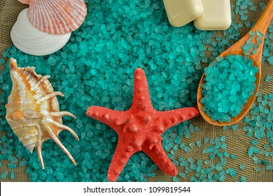 A Wooden Spoon Filled With Blue Sea Salt For Spa Treatments Is Located Next To The Red Starfish And Soap