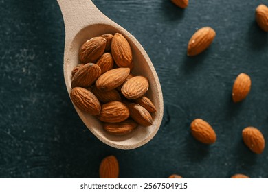 Wooden spoon filled with raw almonds on a rustic dark surface. Scattered almonds create a natural and wholesome ambiance. A burlap background adds warmth and texture to the scene.