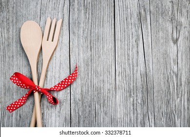 wooden spoon and fork tied up with a red ribbon on rustic background - Powered by Shutterstock