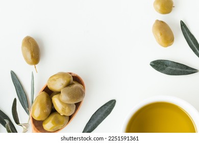 Wooden spoon full of green olives next to olive oil and leaves on the white background. Flat lay. Traditional Greek and Italian food ingredients Foto Stok