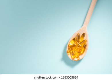 Wooden spoon of Omega-3 capsules on blue background with copyspace. Healthcare, wellbeing and supplements. - Shutterstock ID 1683005884
