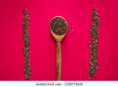 Wooden Spoon With Scattered Chia Seeds On A Red Background