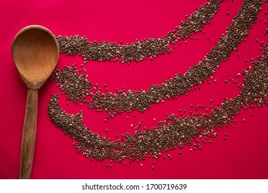 Wooden Spoon With Scattered Chia Seeds On A Red Background