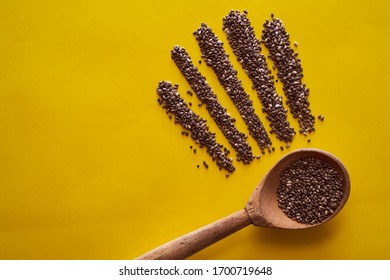 Wooden Spoon With Scattered Chia Seeds. Yellow Background