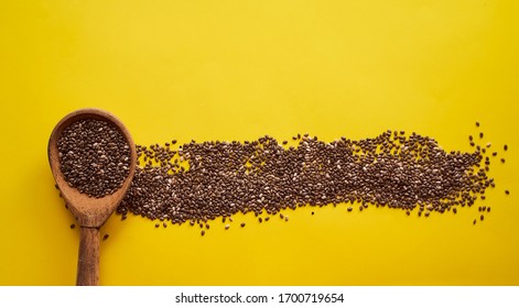 Wooden Spoon With Scattered Chia Seeds Lies On A Yellow Background. Banner