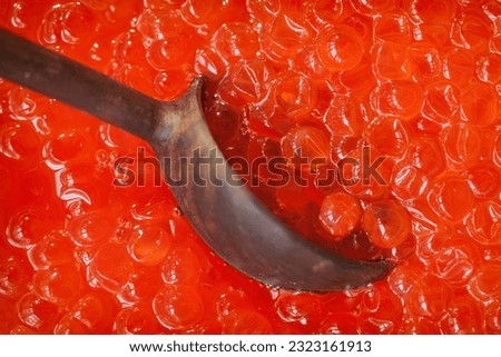 Wooden spoon taking natural red salmon caviar close-up