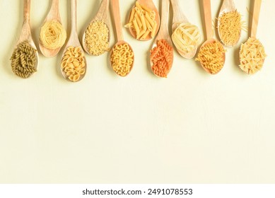 Wooden spoons with different raw tasty pasta on light beige background - Powered by Shutterstock