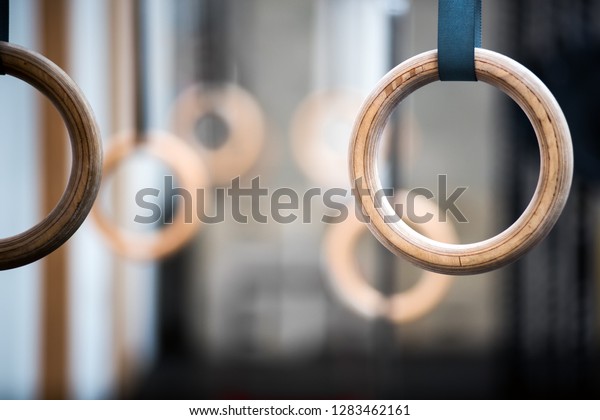Wooden sport rings in gym, viewed in close-up\
with selective focus. Pair of rings is blurred in background.\
Gymnastics equipment\
concept